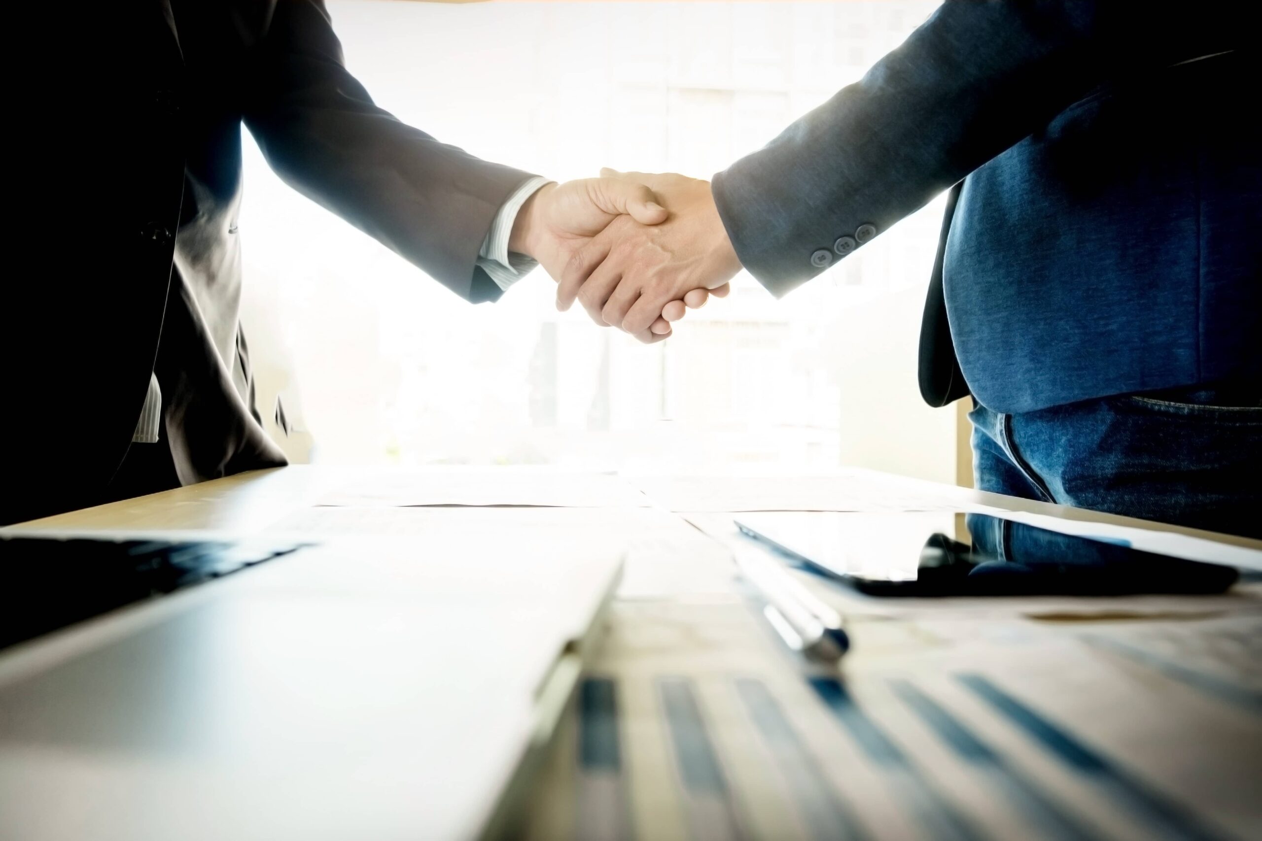 Business handshake between two professionals in suits, symbolizing successful partnership and collaboration in a corporate setting